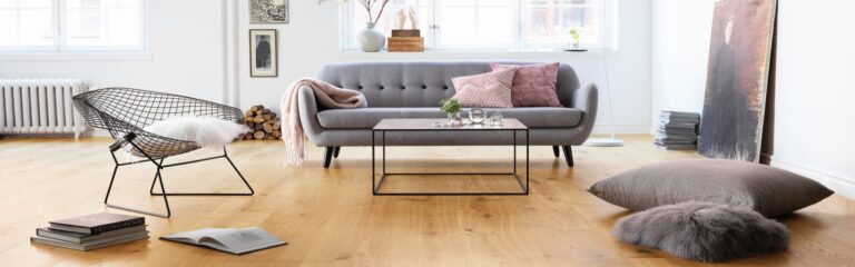Ein Wohnzimmer mit einer grauen Couch und Kissen. Firmenadresse